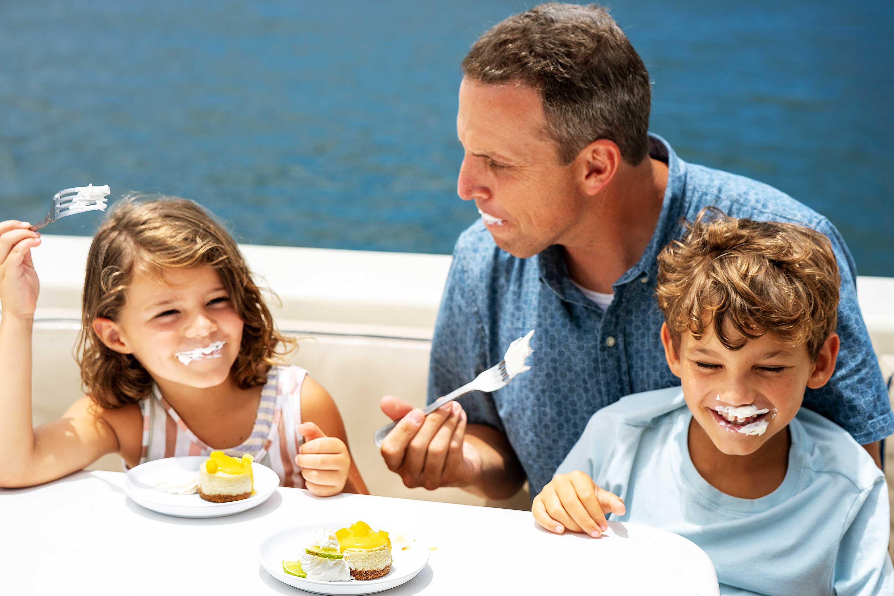 Father and kids eat lime cheesecake served for dessert on Capt Andy Kauai dinner cruises
